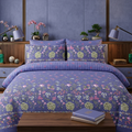 Periwinkle Hydrangea Garden Bedsheet Set with green hydrangea clusters pink tulips and white wildflowers on rich periwinkle violet-blue background styled in a luxury bedroom