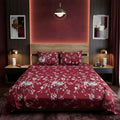 Burgundy Floral Vine Bedsheet Set with trailing silver-grey rose vines and white blossoms on deep burgundy maroon background styled on a luxury bed