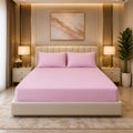 Premium pink fitted mattress cover with matching pillowcases in a luxury bedroom with gold accents and warm lighting