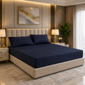 Premium navy blue fitted mattress cover with matching pillowcases in a luxury bedroom with gold accents and crystal lamps