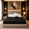 Premium black fitted mattress cover on a luxury hotel-style bed with white pillows and gold accents